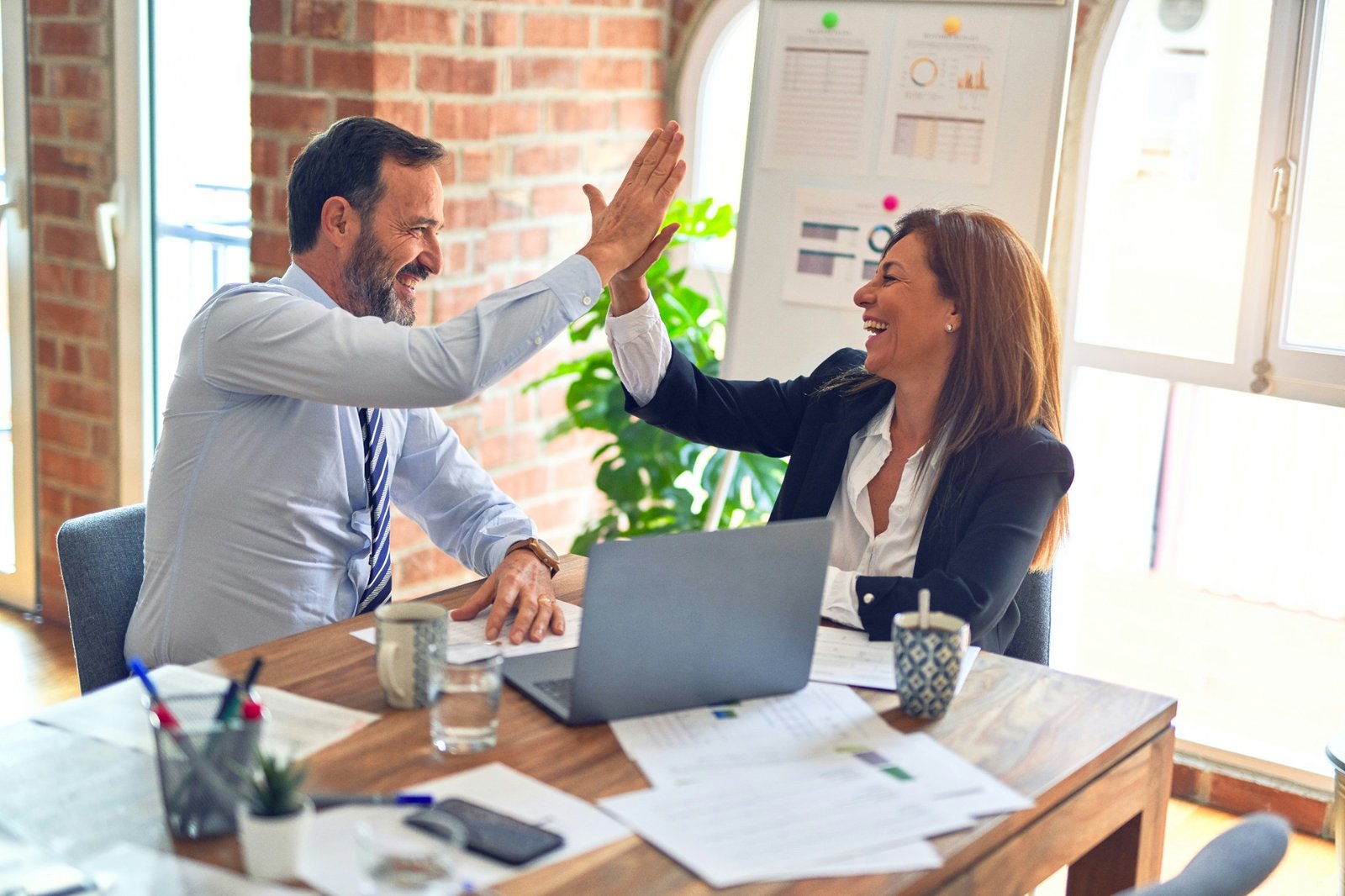 Two business professionals celebrating a successful collaboration in a bright office